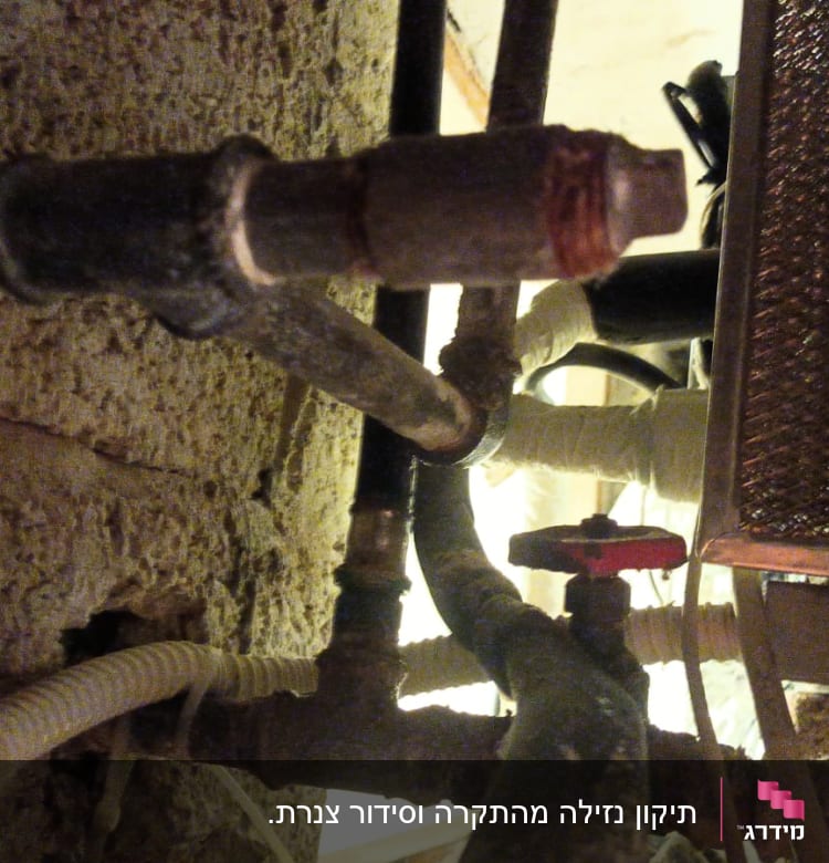 צינורות מתכת וברז אדום במערכת אינסטלציה